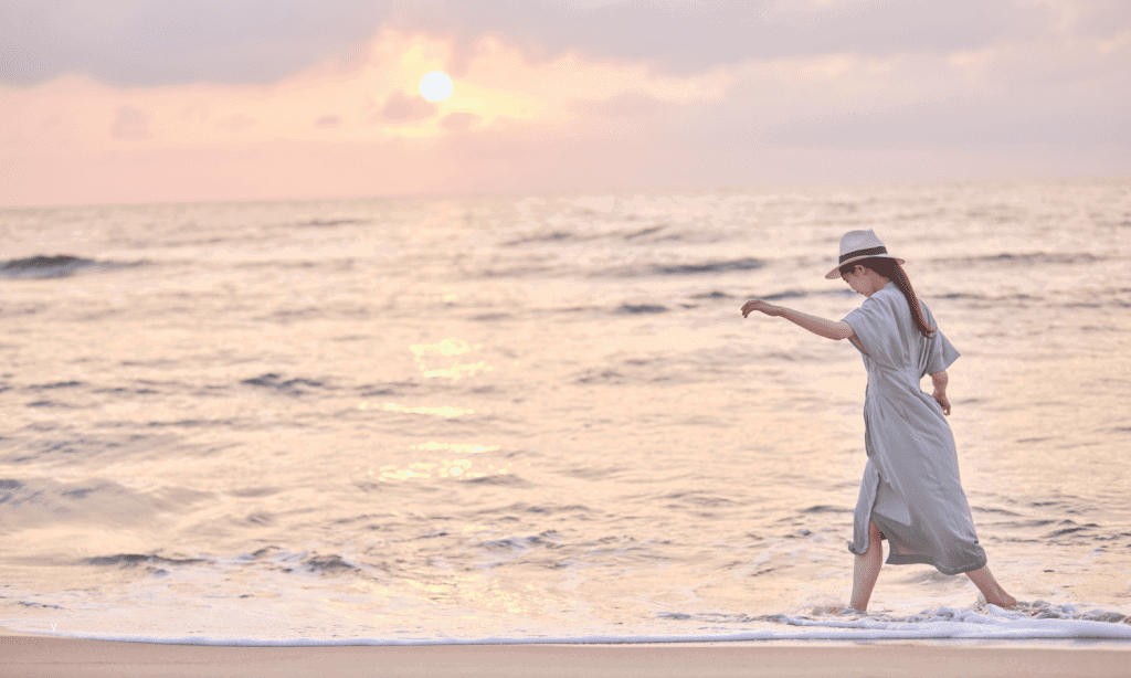 Woman walking along Wellington beach at sunrise — symbolising recovery after pelvic organ prolapse physiotherapy.