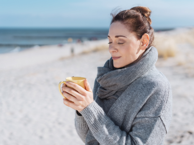 Relaxed woman enjoying a warm drink outdoors in winter, staying comfortable despite leaking when you cough or sneeze being common this season
